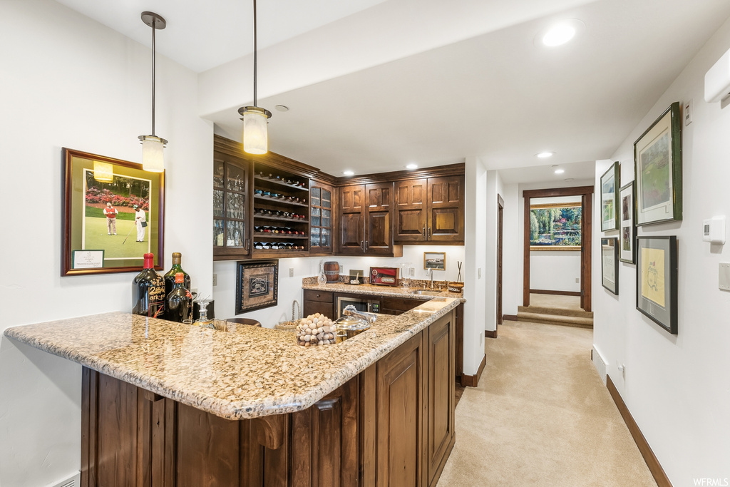 Kitchen with natural light, light flooring, light granite-like countertops, pendant lighting, and dark brown cabinetry