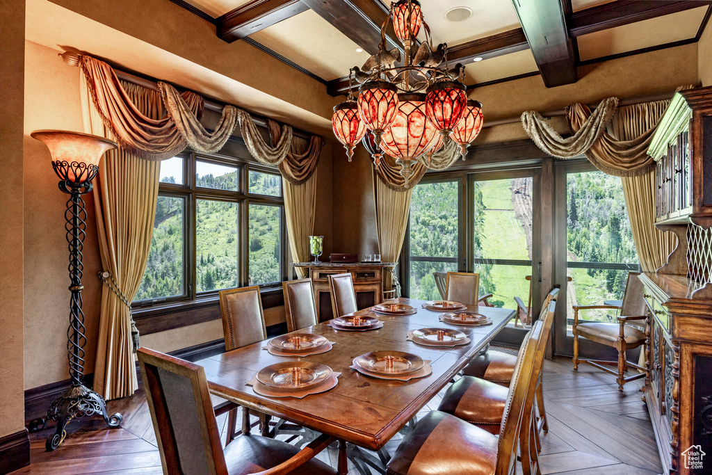 Dining space with dark parquet floors, a notable chandelier, coffered ceiling, and beamed ceiling