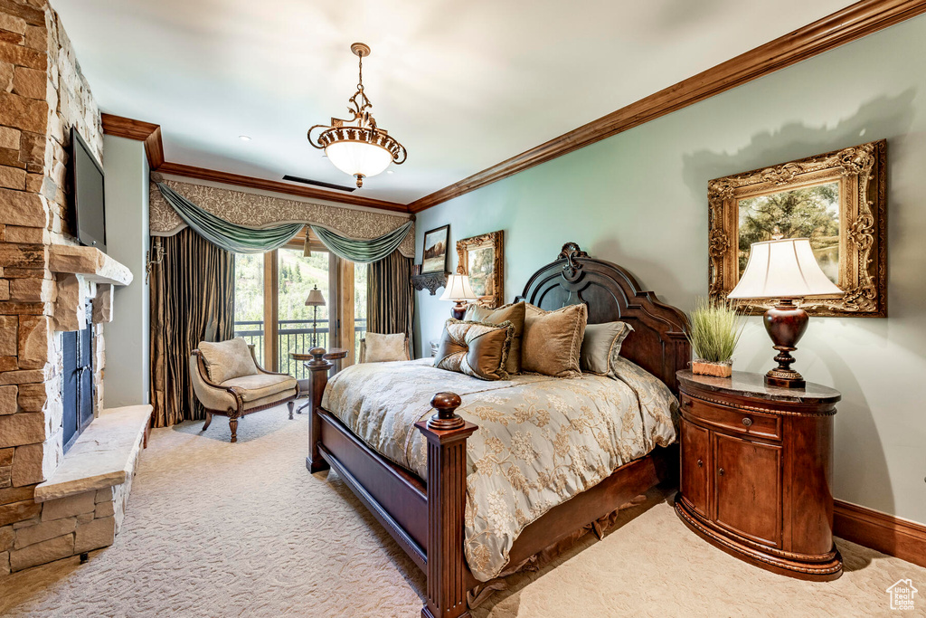 Carpeted bedroom featuring crown molding, a stone fireplace, and access to exterior