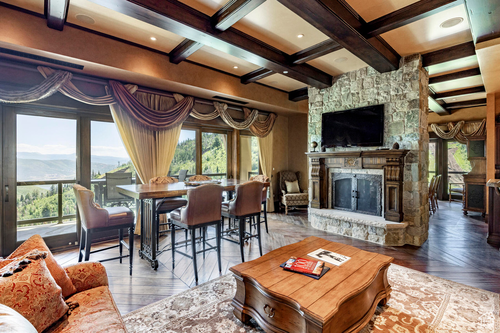 Living room with a stone fireplace, a mountain view, dark parquet flooring, coffered ceiling, and beamed ceiling