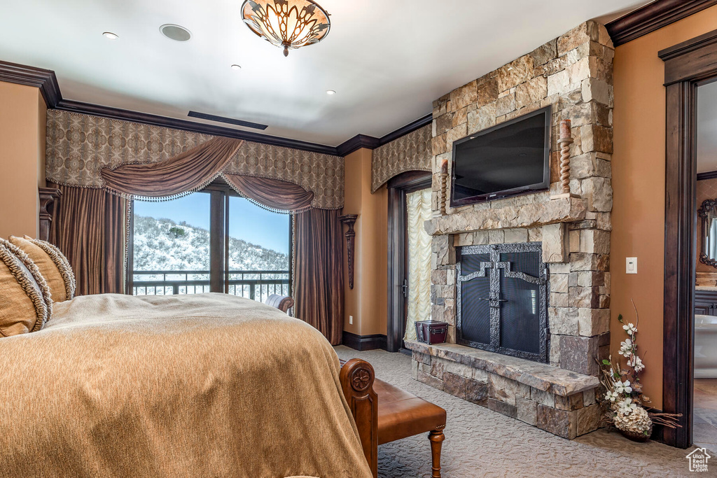Carpeted bedroom with crown molding, a stone fireplace, and access to exterior