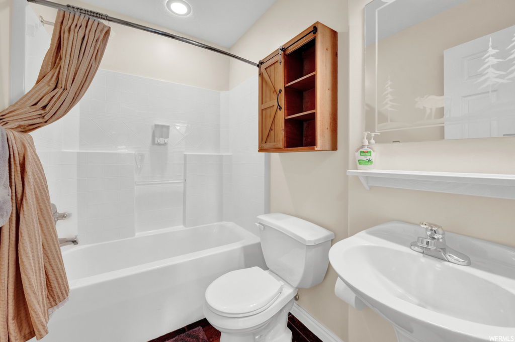 Full bathroom with shower curtain, sink, bathtub / shower combination, dual mirrors, and toilet