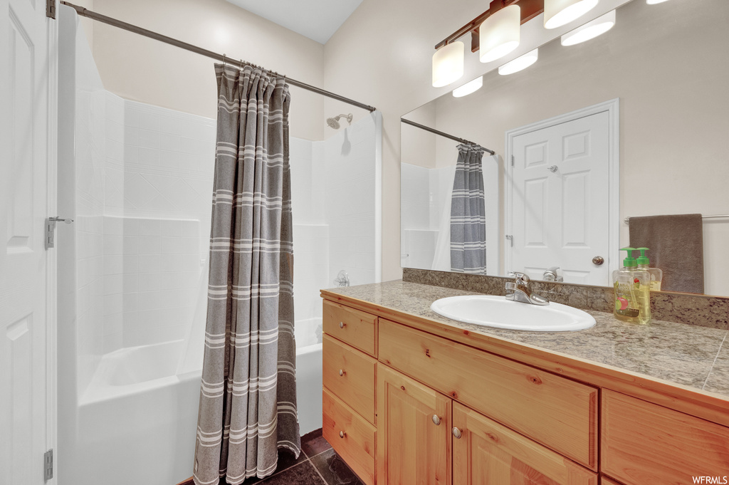 Bathroom with tile floors, mirror, shower / tub combination, shower curtain, and large vanity