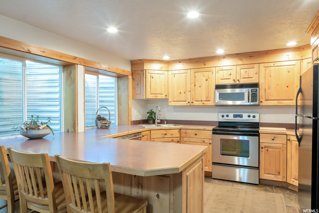 Kitchen with natural light, refrigerator, range oven, stainless steel microwave, light countertops, and light flooring