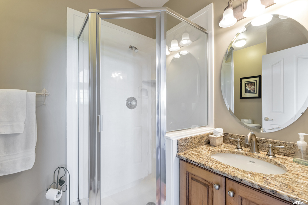 Bathroom featuring mirror, vanity, and shower with shower door