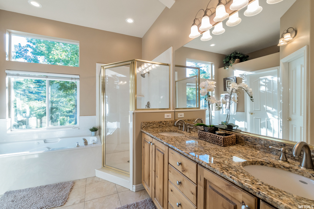 Bathroom with tile floors, plenty of natural light, mirror, double sink vanity, and independent shower and bath