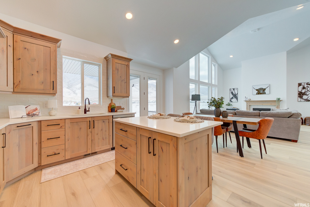 Kitchen with light wood-type flooring, a center island, tasteful backsplash, and sink
