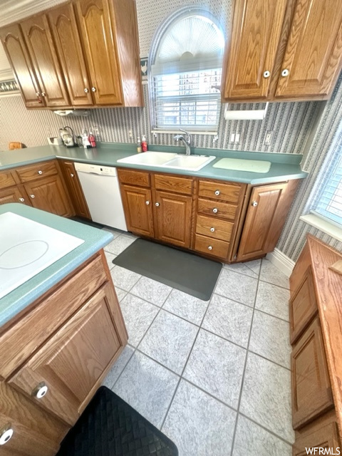 Kitchen with white appliances, light tile flooring, plenty of natural light, and sink