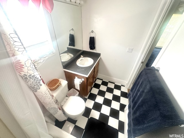 Bathroom featuring natural light, tile floors, shower curtain, mirror, vanity, and toilet
