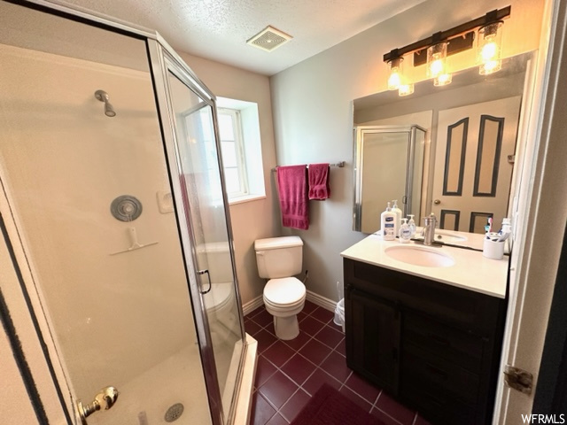 Full bathroom with tile floors, toilet, mirror, vanity, and shower booth
