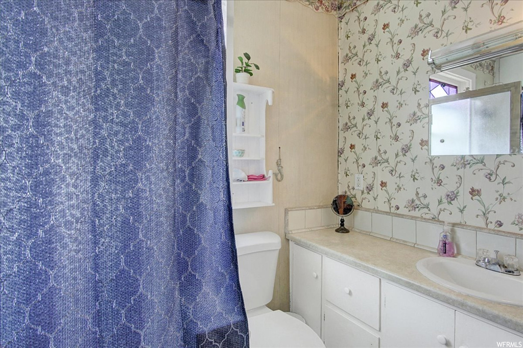 Half bath featuring mirror, vanity, and toilet