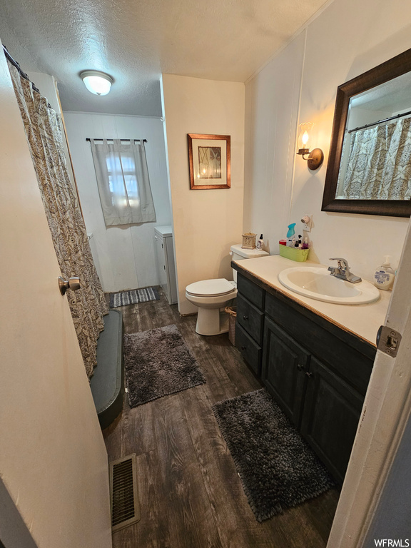 Bathroom with dark hardwood floors, mirror, a textured ceiling, and vanity