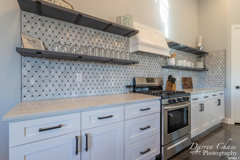 Kitchen with gas range oven, stainless steel finishes, white cabinets, and light countertops