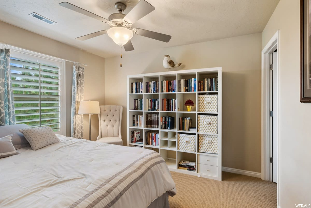 Bedroom featuring a ceiling fan, natural light, and carpet