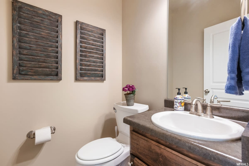 Half bathroom featuring toilet, mirror, and vanity