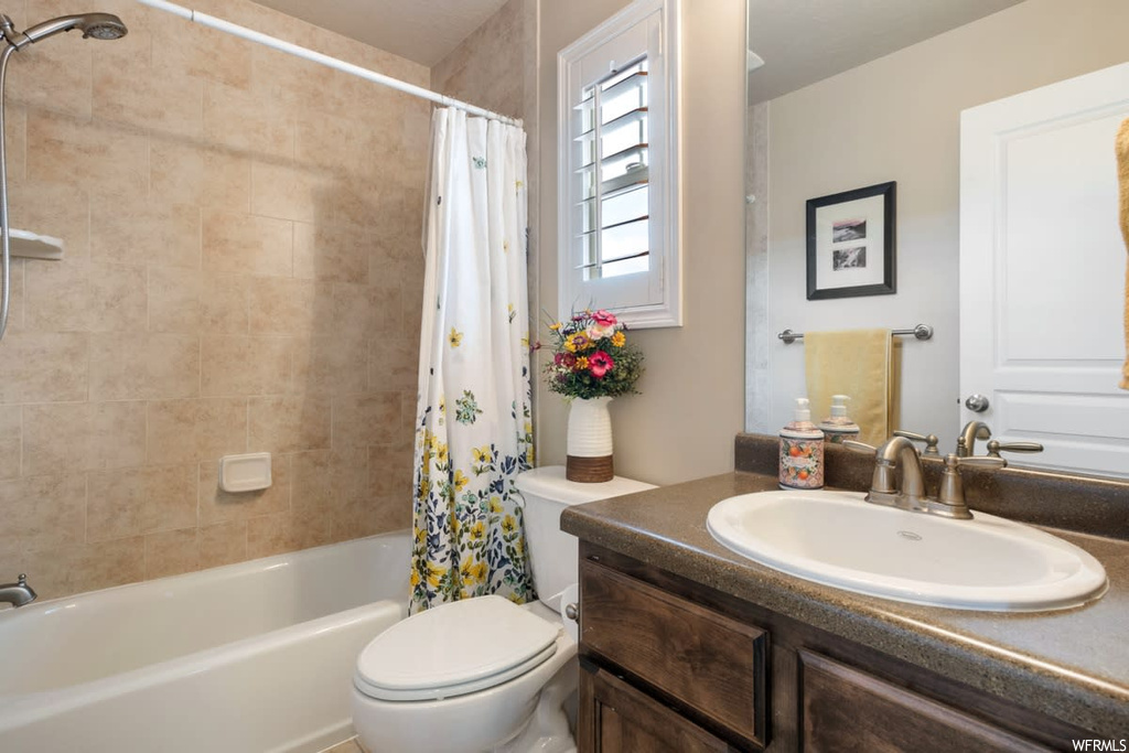 Full bathroom featuring natural light, vanity, shower curtain, mirror, toilet, and shower / bath combination