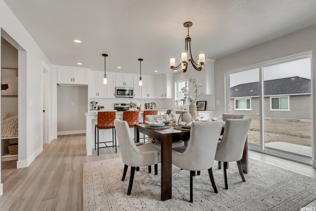 Dining room with hardwood floors, a notable chandelier, natural light, and stainless steel microwave