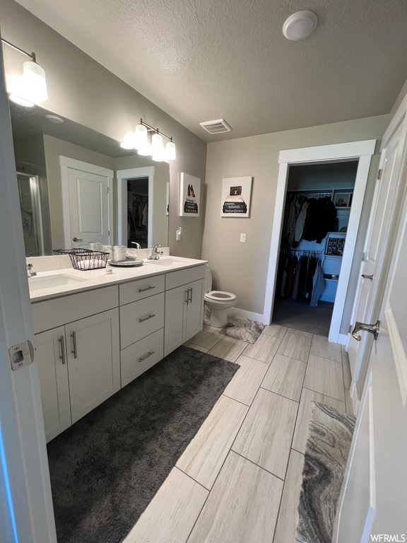 Half bath with tile floors, toilet, mirror, and dual vanities