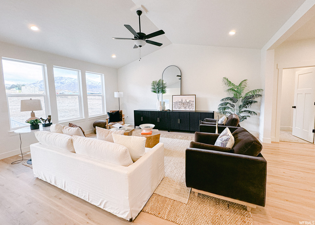 Living room with vaulted ceiling, ceiling fan, and light hardwood / wood-style floors