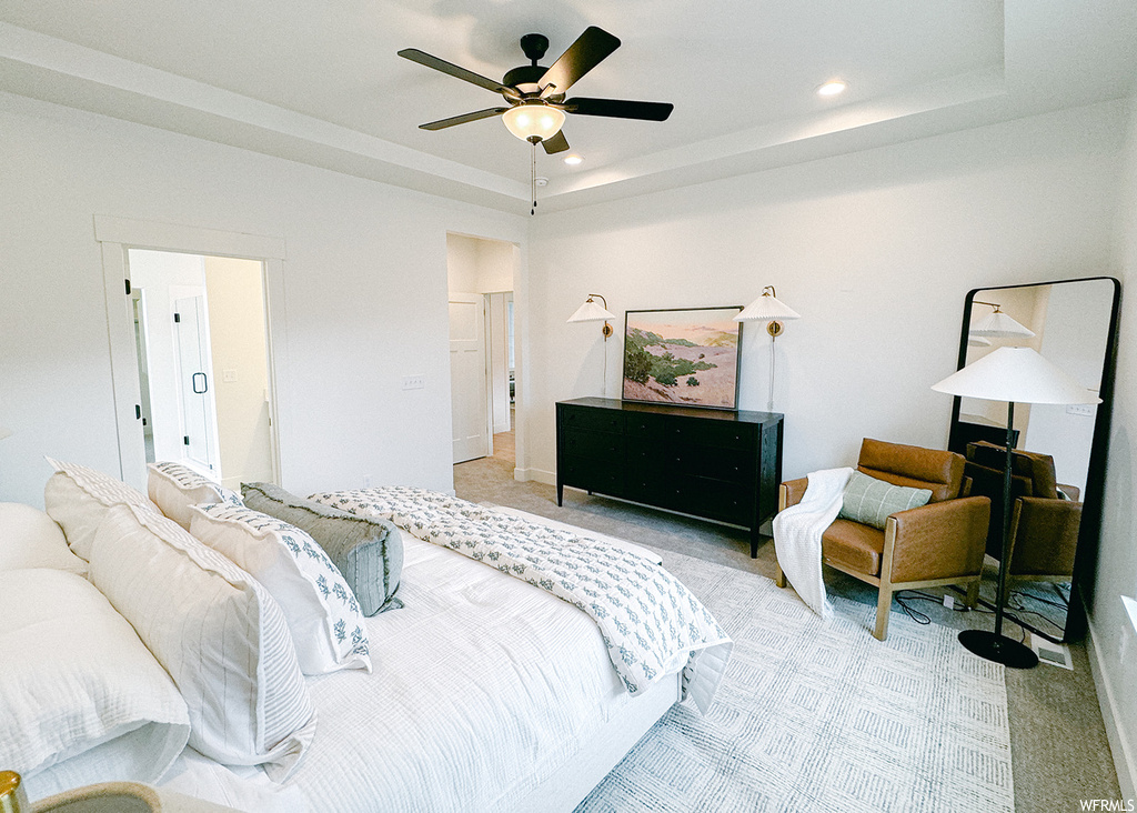 Bedroom featuring ceiling fan, a raised ceiling, and light colored carpet