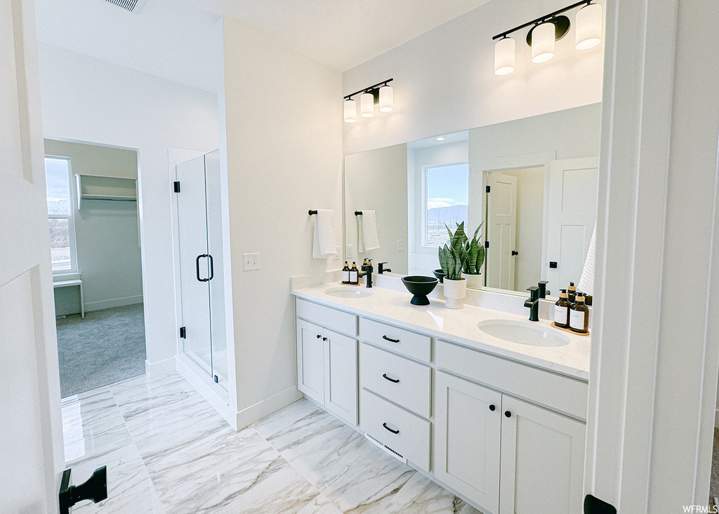 Bathroom featuring an enclosed shower, tile floors, plenty of natural light, and dual bowl vanity