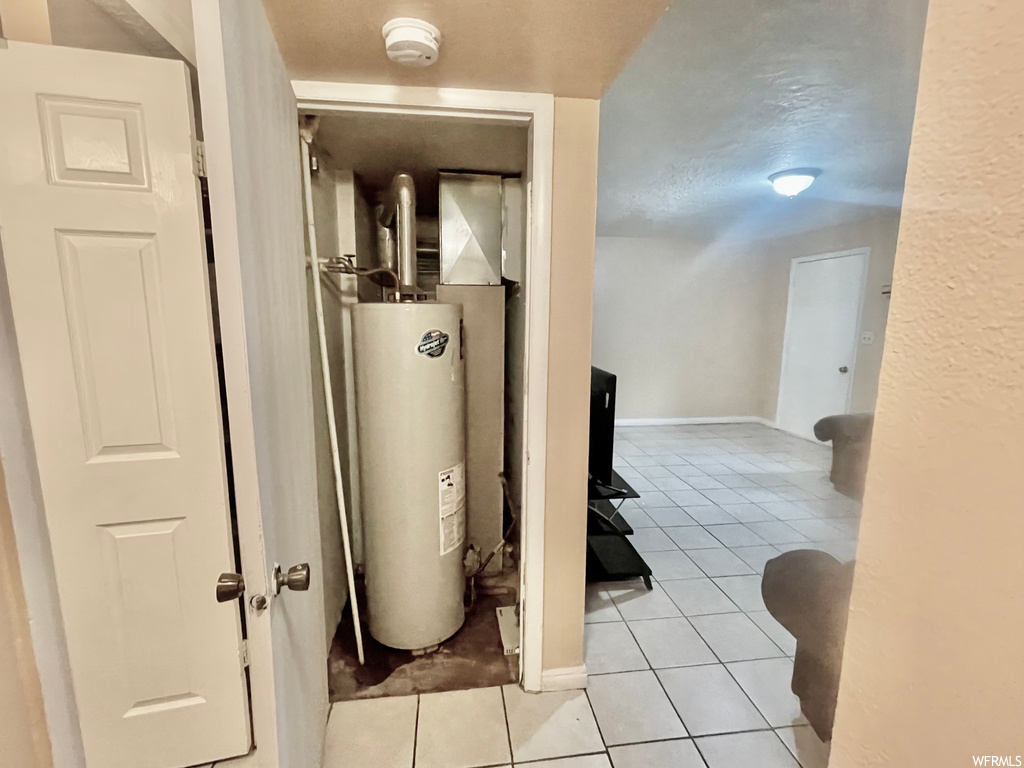 Utility room featuring tile flooring and water heater