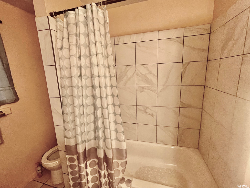 Bathroom featuring shower curtain, toilet, and bath / shower combination