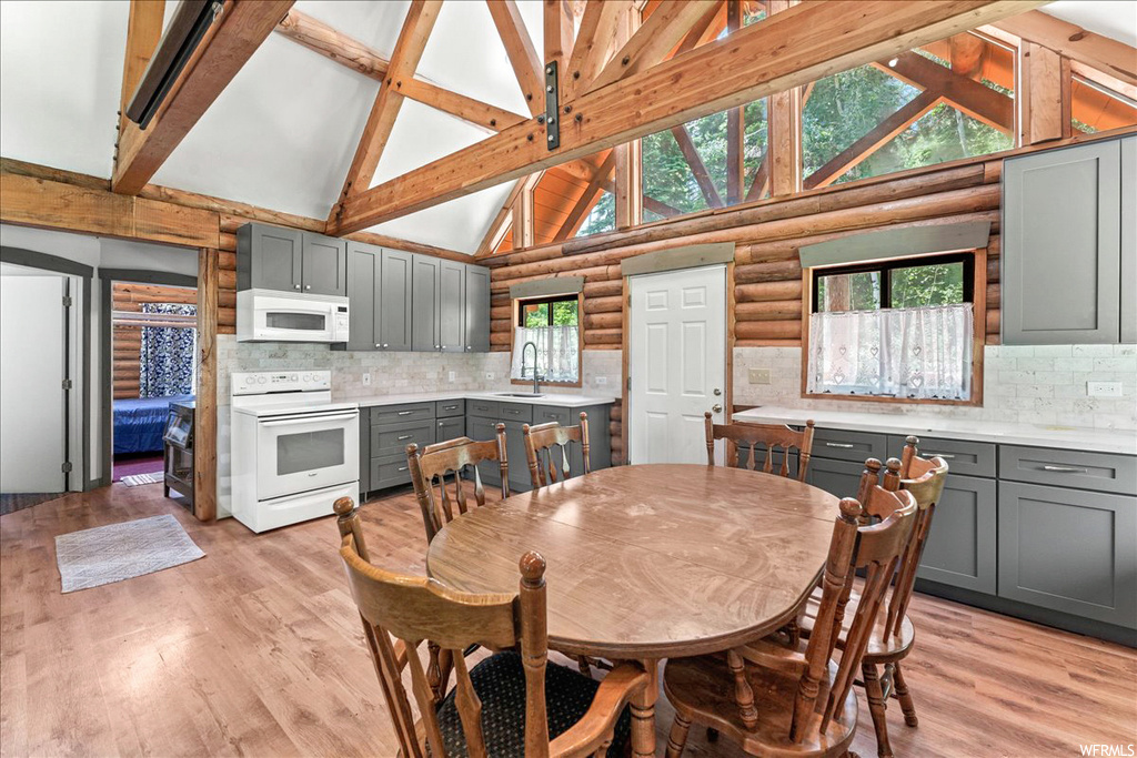 Wood floored dining area with vaulted ceiling with beams, natural light, and microwave