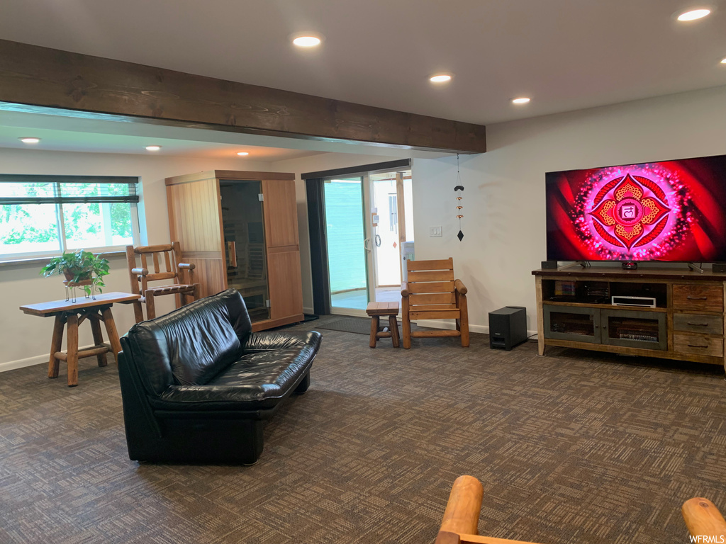 Living room with wood beam ceiling, natural light, carpet, and TV