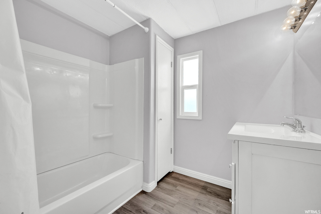 Bathroom featuring wood-type flooring, natural light, vanity, and shower / bathtub combination