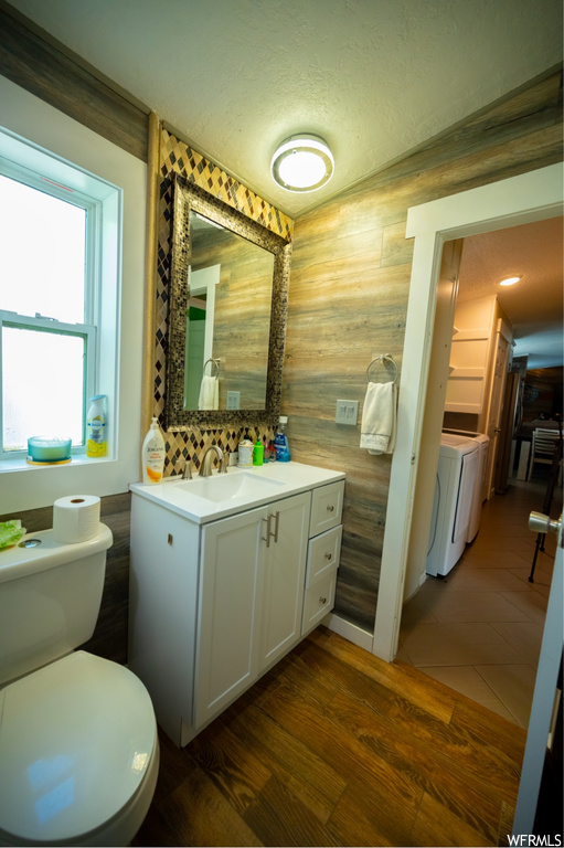 Half bathroom with natural light, hardwood flooring, mirror, toilet, and vanity