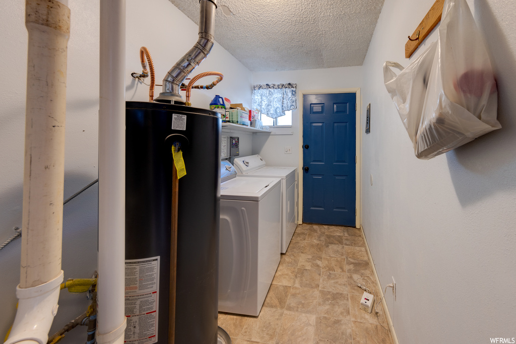 Clothes washing area with tile flooring, natural light, water heater, and separate washer and dryer