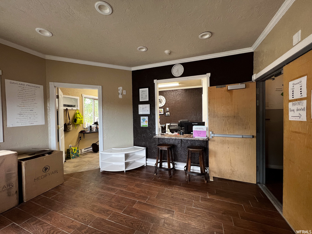 Office space featuring dark hardwood floors, crown molding, and a textured ceiling