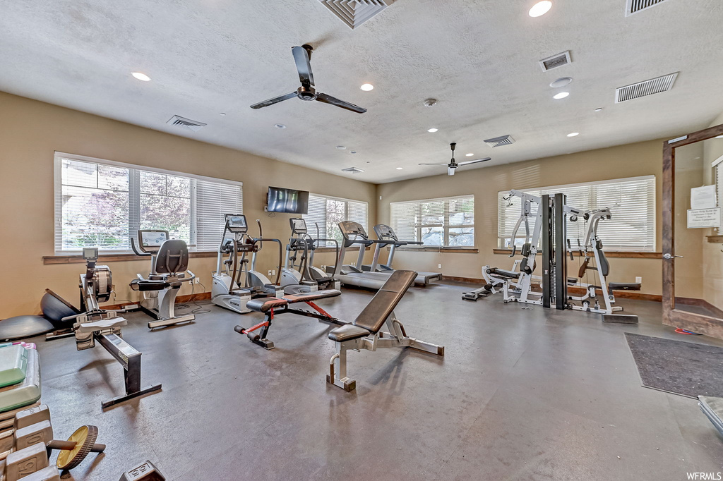 Gym with ceiling fan, a textured ceiling, and TV