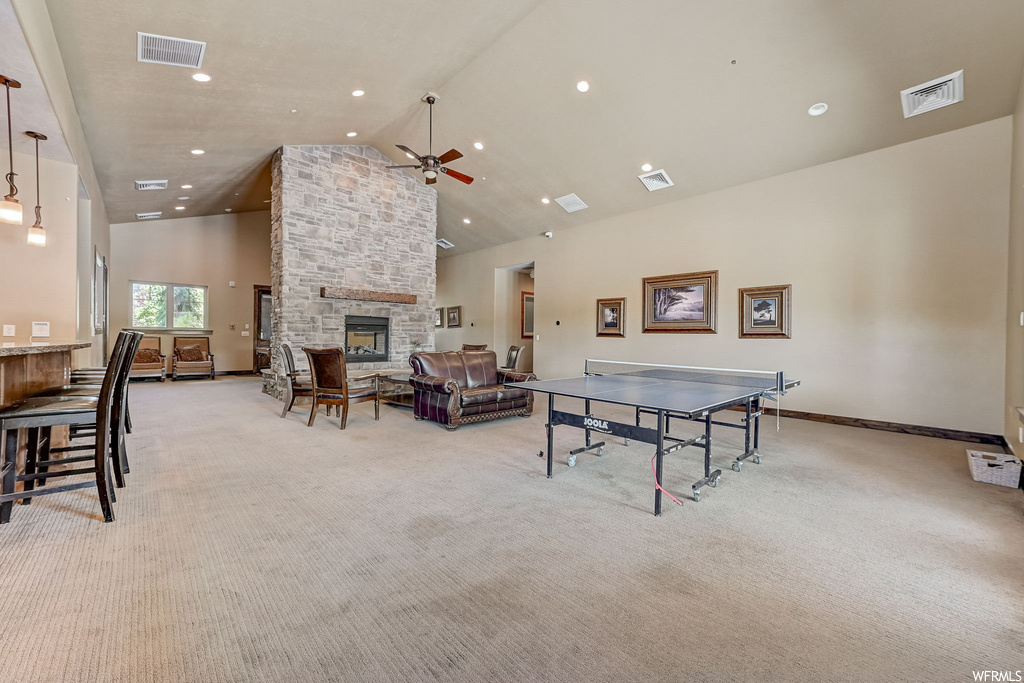 Playroom featuring ceiling fan, a fireplace, a high ceiling, light carpet, and lofted ceiling