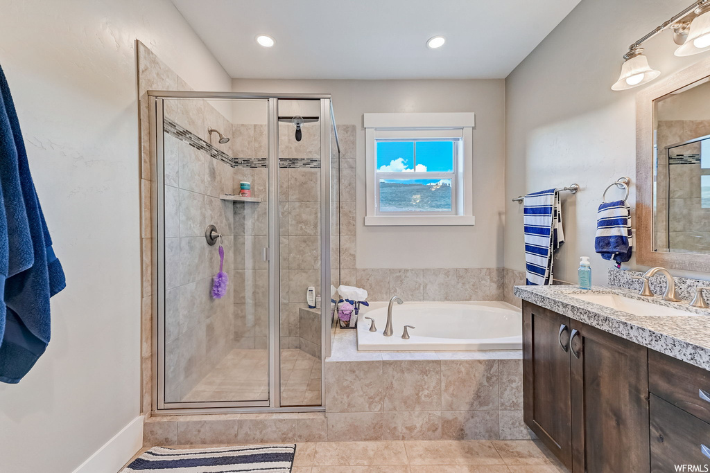 Bathroom with mirror, light tile flooring, vanity, and separate shower and tub enclosures