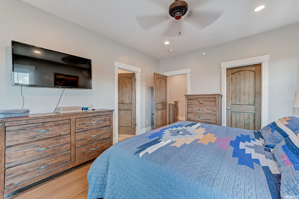 Bedroom with TV, ceiling fan, and light parquet floors