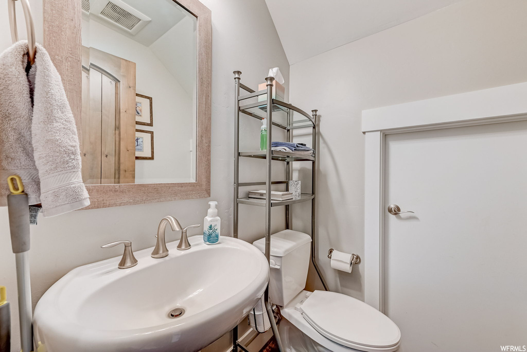 Bathroom featuring sink, mirror, and lofted ceiling