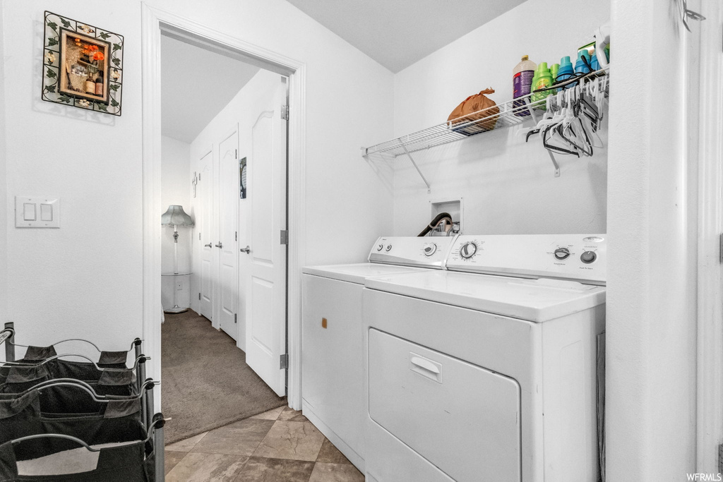 Laundry area featuring light carpet and washer and clothes dryer