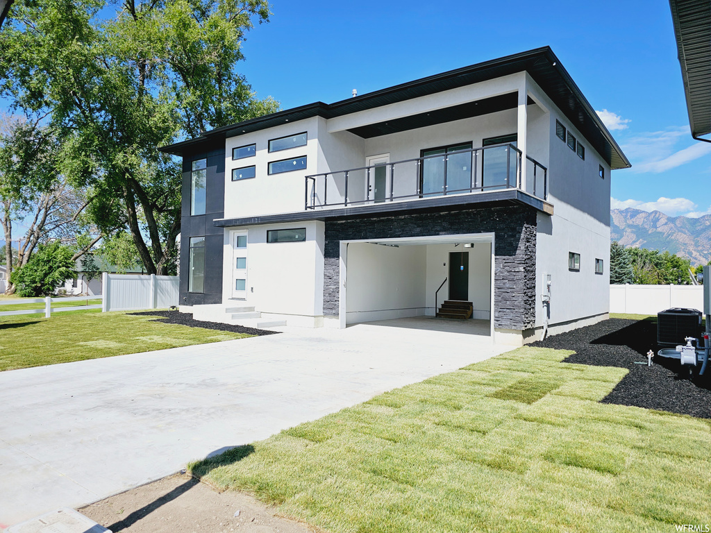 Modern home with a front yard, a patio area, and balcony