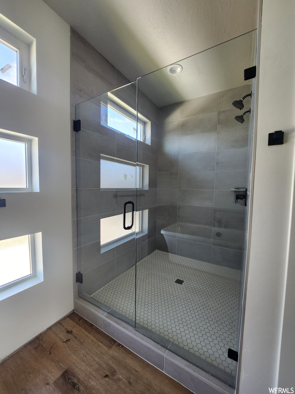 Bathroom featuring wood-type flooring, a shower with door, and a wealth of natural light