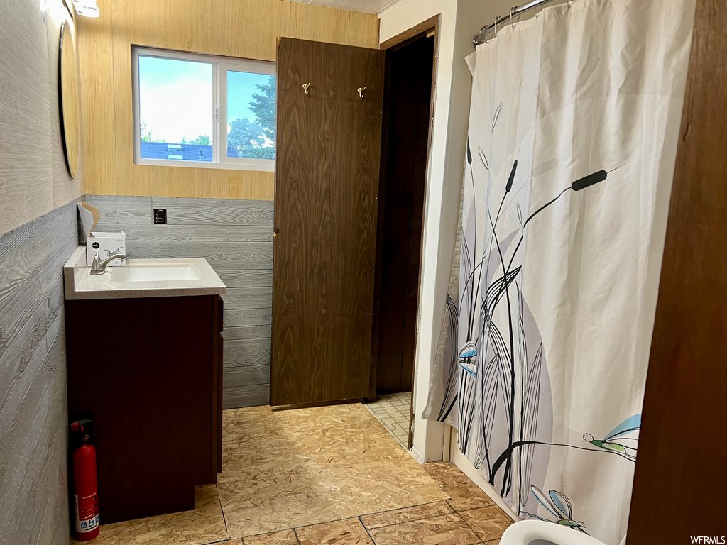 Bathroom featuring vanity, light tile floors, and wooden walls