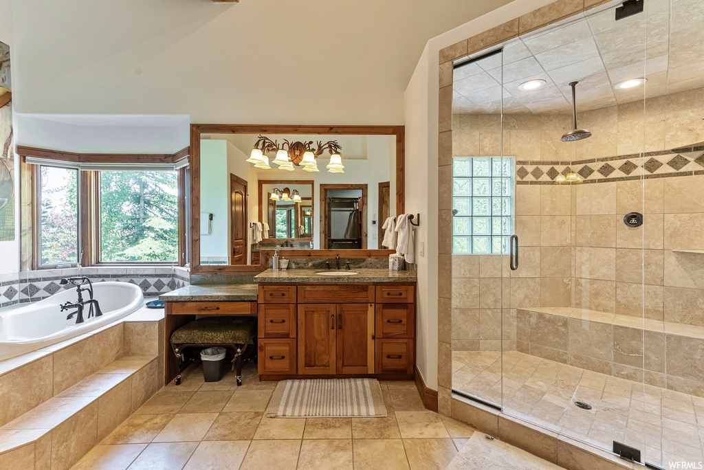 Bathroom featuring vanity, light tile floors, separate shower and tub enclosures, and mirror
