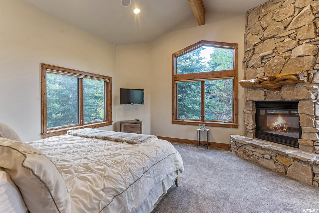 Bedroom with a fireplace, multiple windows, light carpet, TV, and lofted ceiling with beams