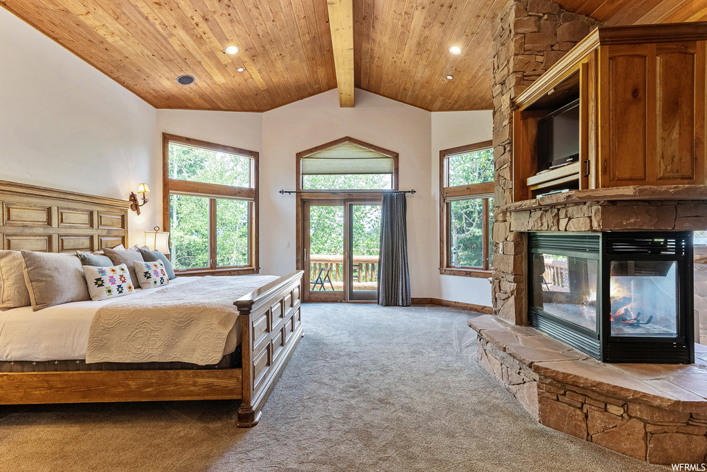 Carpeted bedroom with a fireplace, multiple windows, a high ceiling, wood ceiling, and vaulted ceiling with beams