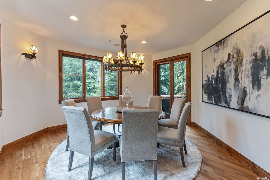 Hardwood floored dining room with a notable chandelier and a wealth of natural light
