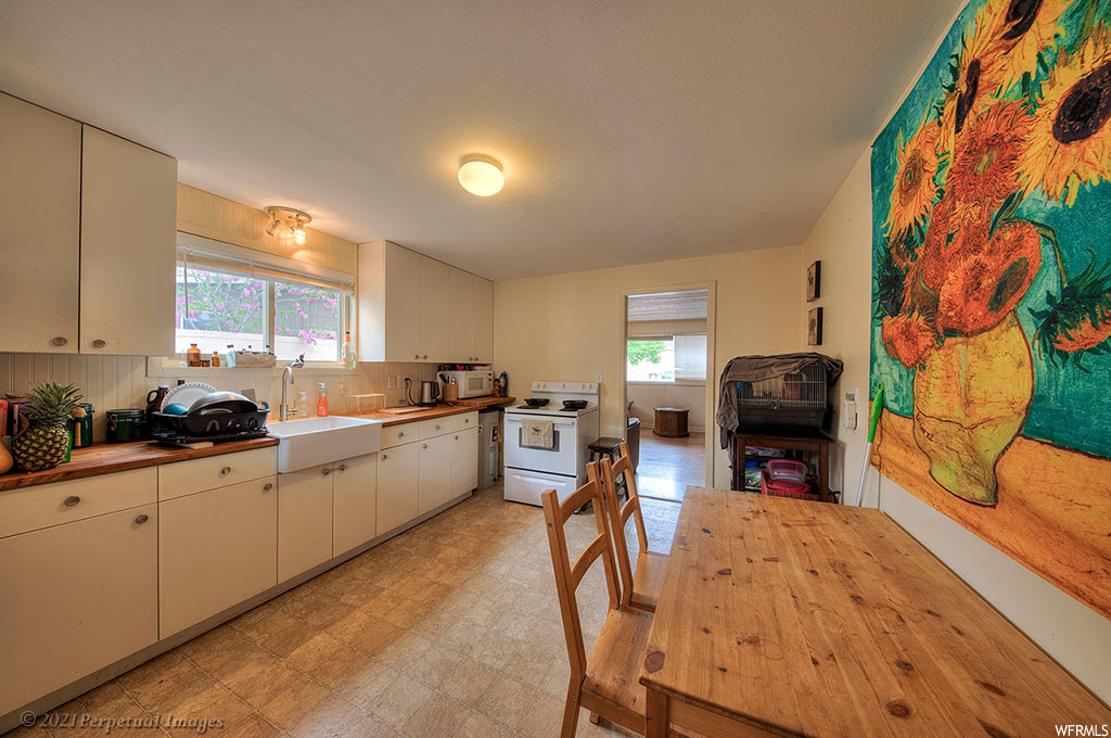 Kitchen featuring backsplash, light tile floors, a healthy amount of sunlight, and white range