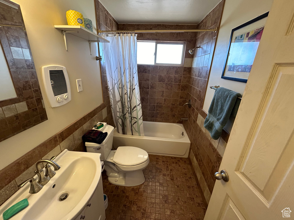 Full bathroom featuring shower / tub combo with curtain, sink, tile walls, and tile floors