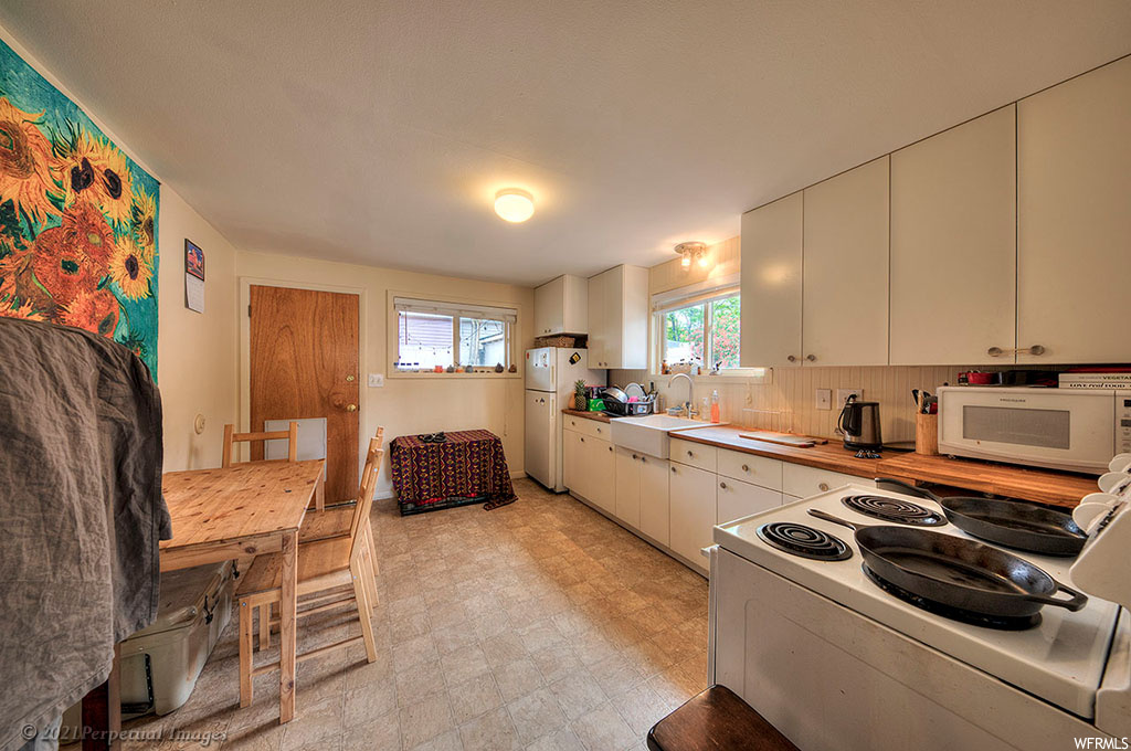 Kitchen featuring backsplash, light tile floors, and white appliances