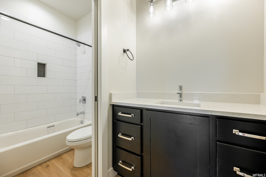 Full bathroom with vanity, light hardwood flooring, and tiled shower / bath combo